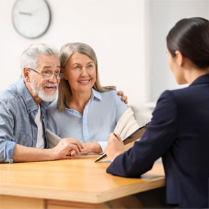 Senior couple consulting with a professional advisor at a desk in an office setting