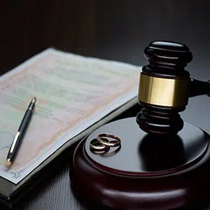 Judge's gavel, wedding rings, and legal document symbolizing divorce proceedings.